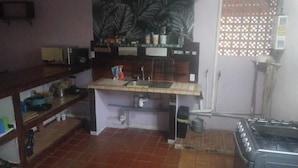 A compact kitchen with a sink, stove, and various kitchen items on shelves.