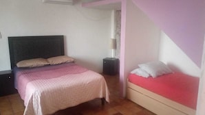 A bedroom with a large bed, a smaller bed, a nightstand, and a window.