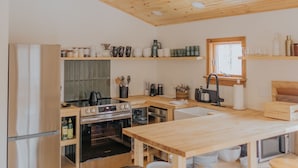 A modern kitchen with wooden beams, stainless steel appliances, and wooden stools.