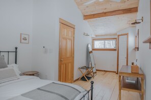 A bedroom with a bed, wooden door, and a window.
