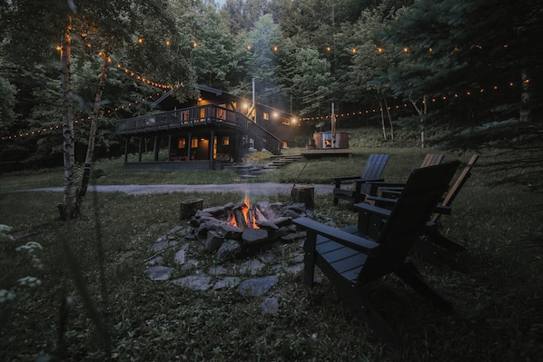 Une cabane avec une terrasse, un foyer et des guirlandes lumineuses.