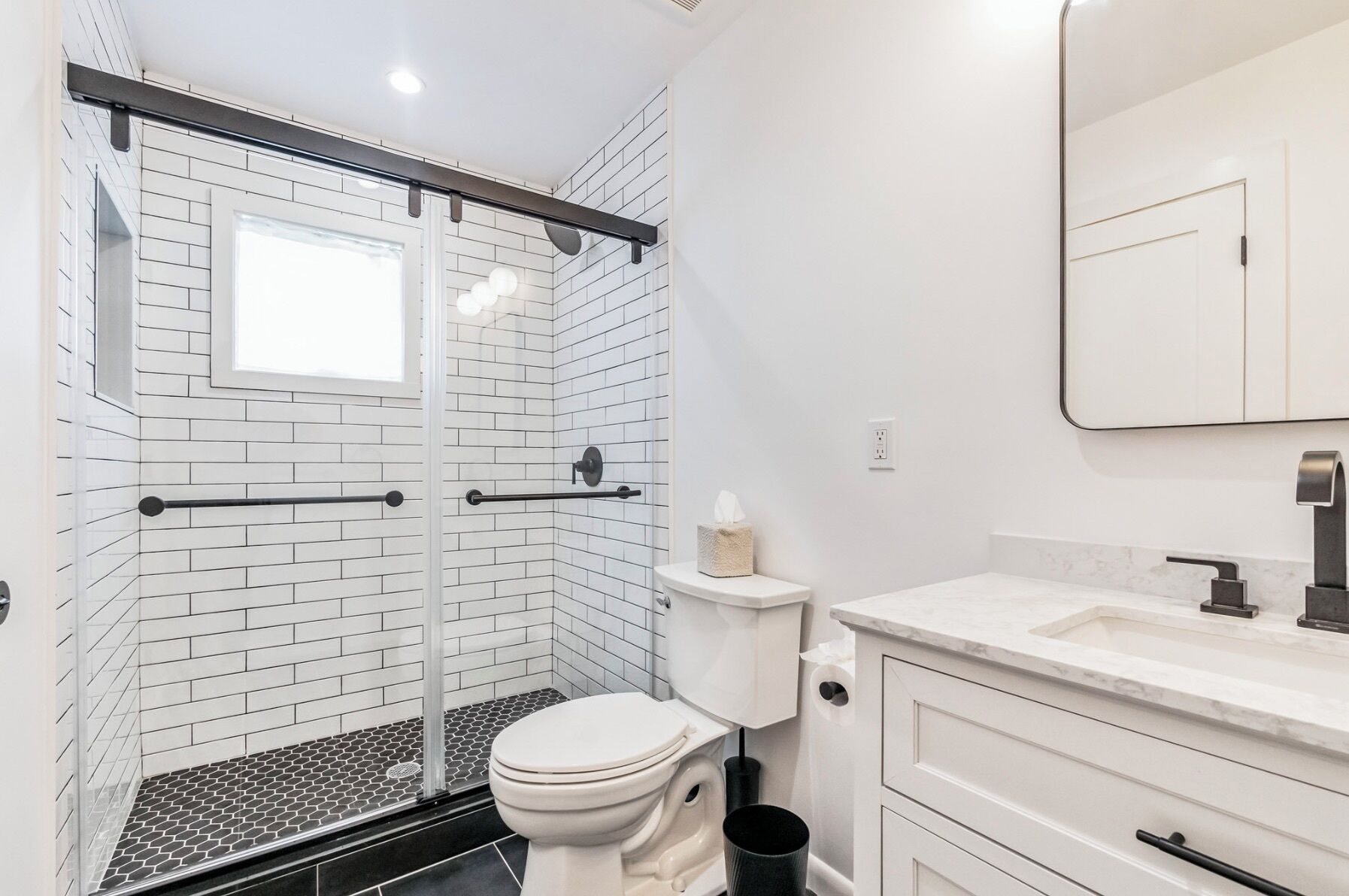Ein Badezimmer mit Toilette, einer Dusche mit Glastür und einem Waschbecken mit Spiegel.