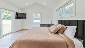 Un dormitorio con una cama grande, un televisor montado en la pared y un escritorio con una silla.
