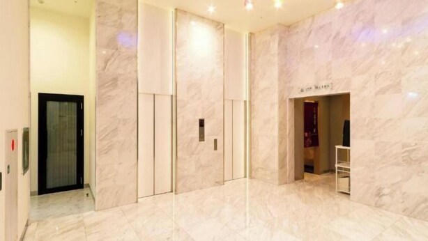 A modern hotel lobby with marble flooring, a reception desk, and a visible elevator. - Queens Hotel Chitose (Chitose)
