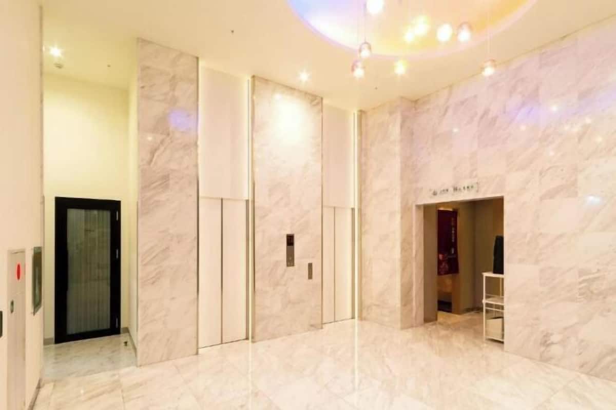 A modern hotel lobby with marble flooring, a reception desk, and a visible elevator.