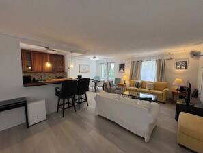 Een compact woongedeelte met een kitchenette, een eethoek en een zithoek met een bank en stoelen.