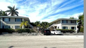 A parking lot with two-story buildings, palm trees, and a clear sky. - Best Kept Atlantic Ave Secret. Fab Location (Delray Beach)