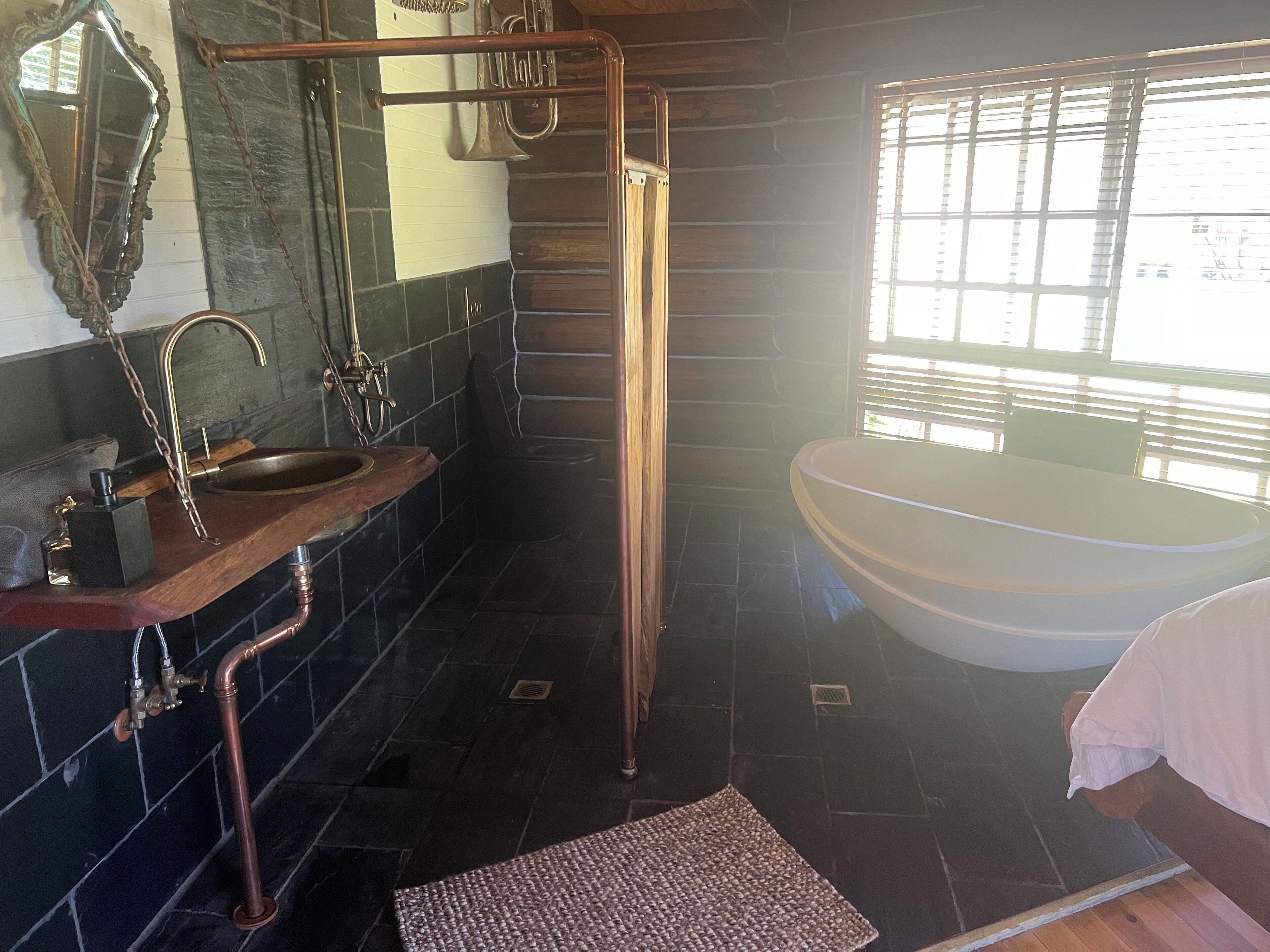 Une salle de bain avec un meuble-lavabo en bois, une baignoire sur pieds et un grand miroir.