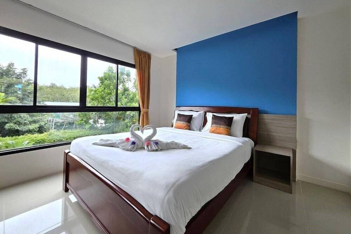Habitación de hotel con una cama grande, vista a zonas verdes por la ventana y una pared de acento azul.