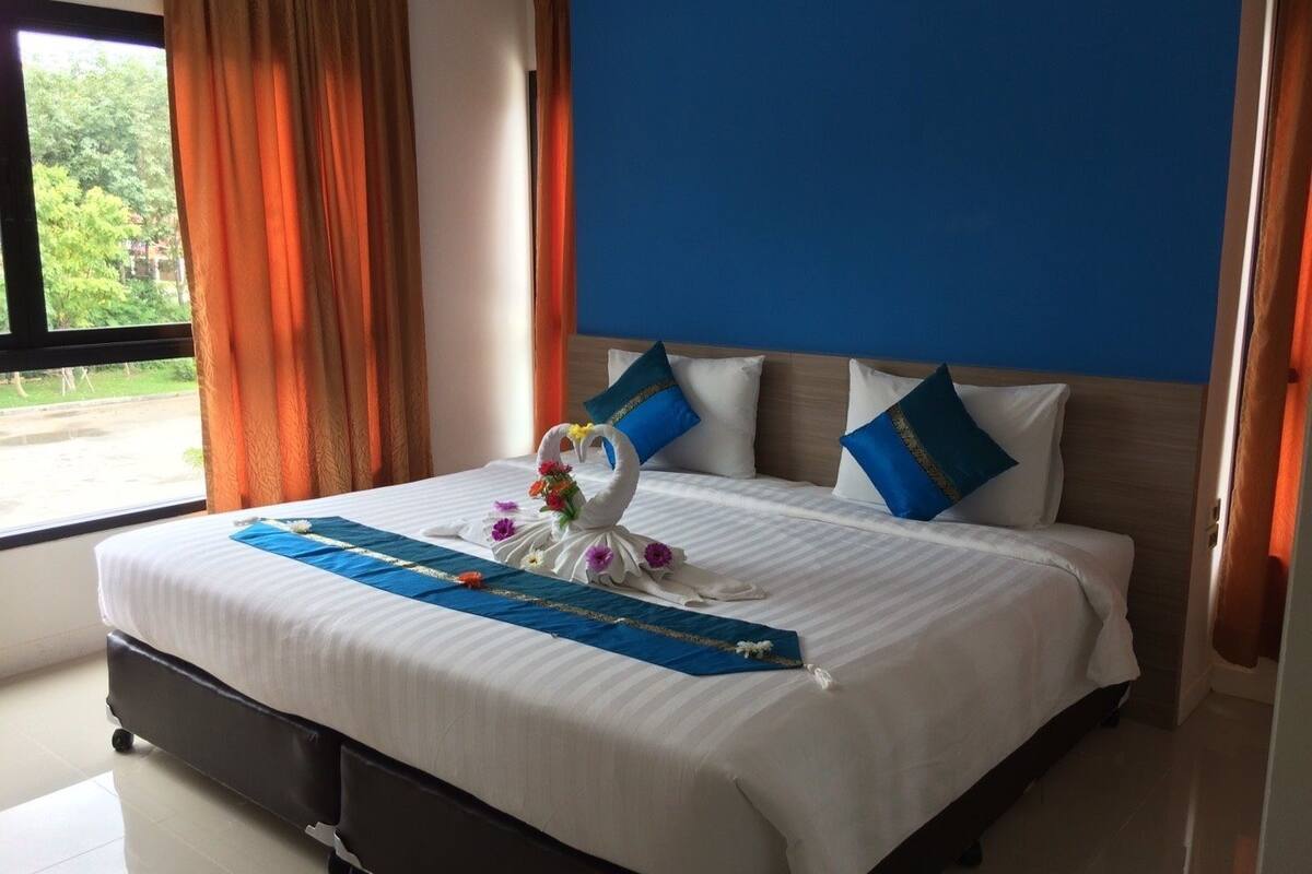 Habitación de hotel con cama, ventana con cortinas y vistas al exterior.