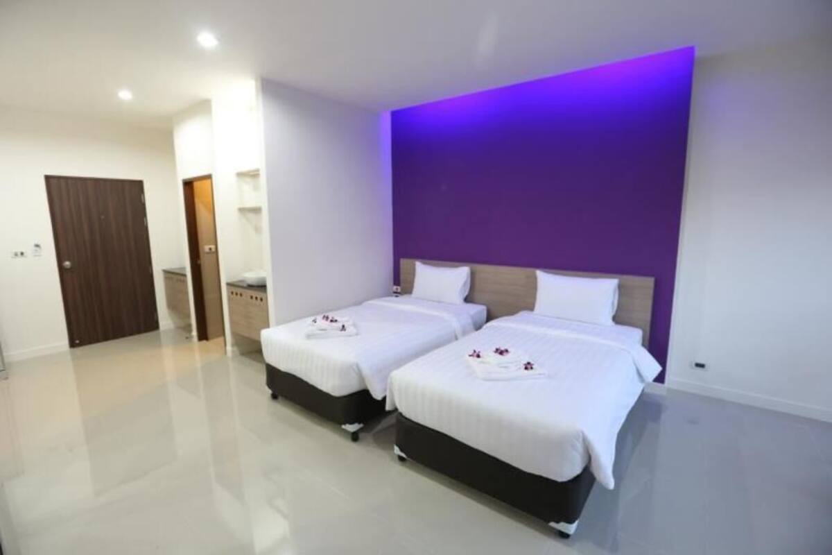 Una habitación de hotel moderna con dos camas, un baño y un pasillo.