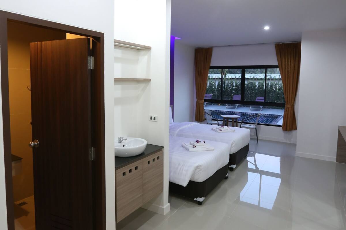 Habitación de hotel moderna con una cama grande, un baño con lavamanos y vistas al exterior a través de una ventana.