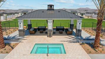 A covered outdoor area with a pool, seating, and a view of residential buildings.