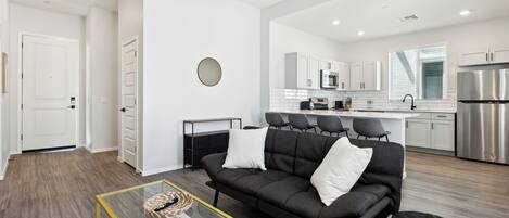 Una sala de estar moderna con un sofá, una mesa de centro de vidrio y un ventilador de techo.