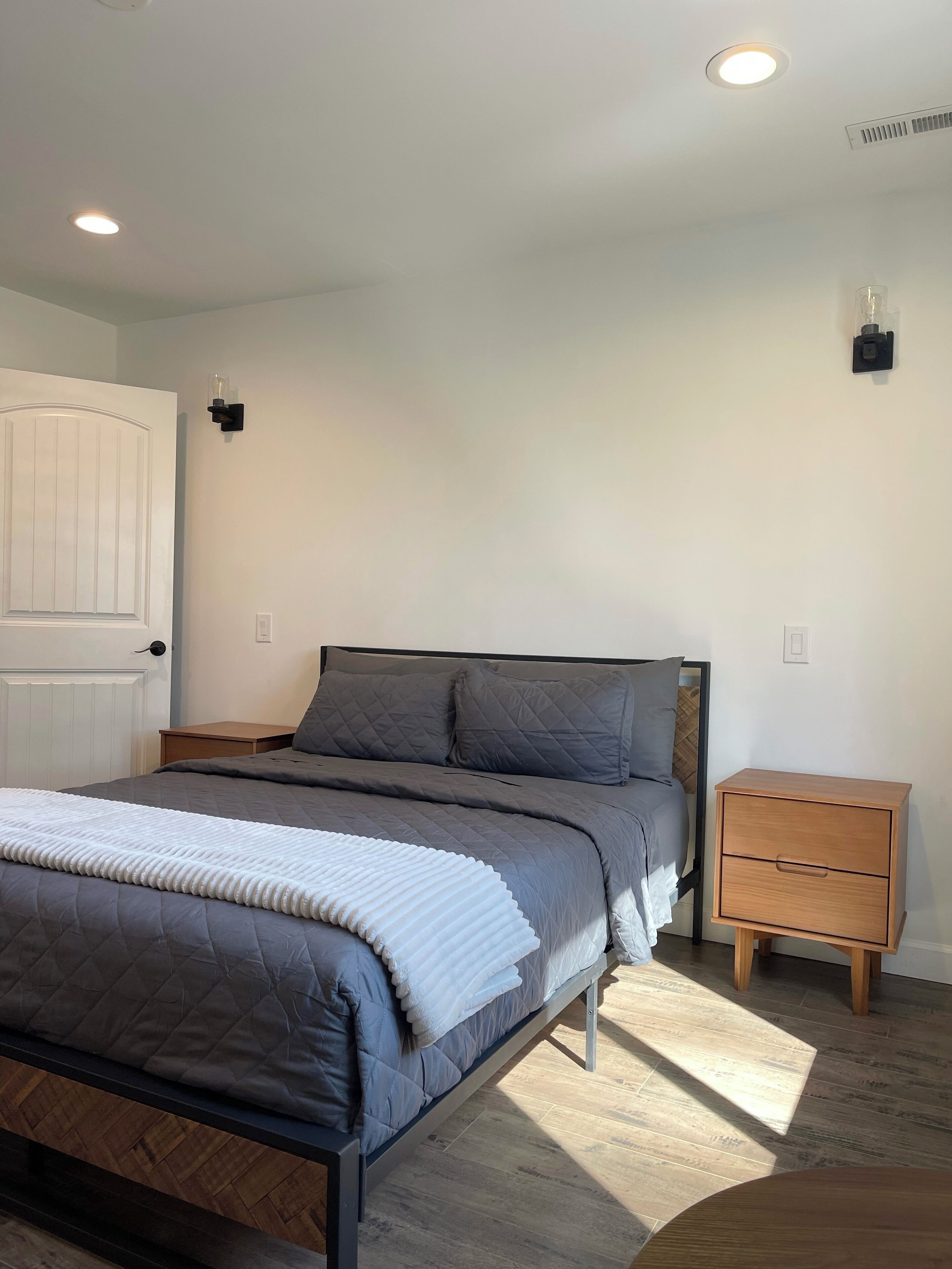 Une chambre à coucher avec un lit, des tables de chevet, une commode et une porte.