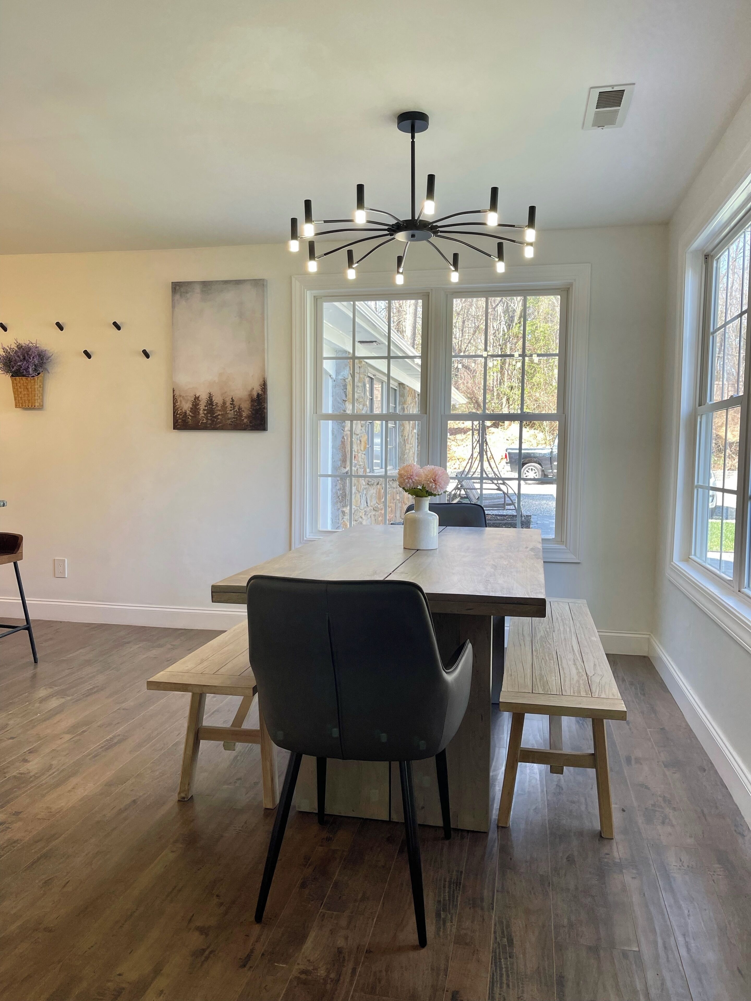 A dining area with a wooden table, black chairs, and a chandelier.