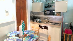 A compact kitchen with a microwave, sink, and a small dining area with a table and chairs. - Bungalow w/ FREE Kayaks, Sailboat, Bicycle Use (Key Largo)