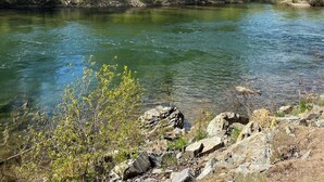 A river with clear water, surrounded by green trees and rocks. - Back Country Getaway. Complete 30/50 RV Site. (Kingston)