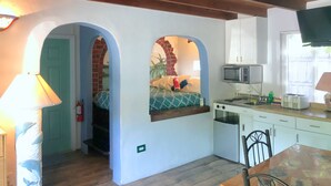 A compact kitchen with a microwave, toaster, and sink. There is a small dining table with chairs. The room has a wooden ceiling and a door leading to another room. - Kayaking, sailing, snorkeling Free w/ Cottage (Key Largo)