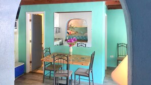 A dining area with a wooden table and chairs, a vase with flowers, and a view through a window. - Kayaking, sailing, snorkeling Free w/ Cottage (Key Largo)