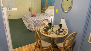 A compact room with a bed, a dining table with chairs, a mirror, and a wall painting. - Free sailing, kayaking, water toys etc w/ Cottage (Key Largo)