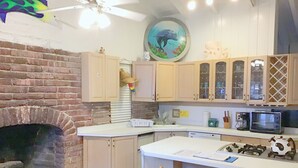 A kitchen with a brick fireplace, wooden cabinets, a microwave, and a coffee maker.