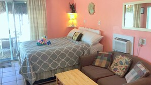 A bedroom with a bed, a nightstand, a lamp, a sofa, and a window with curtains. - Bayside view Cottage , Free kayaks and sailboat (Key Largo)
