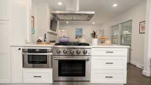 Una cocina moderna con electrodomésticos de acero inoxidable, armarios blancos y un ventanal que proporciona luz natural.