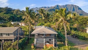 A house with a balcony, surrounded by palm trees and a mountain in the background. - Haena Hale Kauai Beach House (Hanalei)