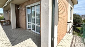 Un balcon doté d’un sol carrelé, d’un banc en bois et d’une porte-fenêtre coulissante.