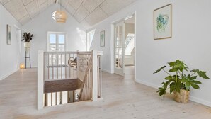 A spacious room with a high ceiling, wooden flooring, and a staircase leading to an upper level.