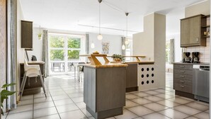 A modern kitchen with a central island, a dining area with a view, and a built-in dishwasher.