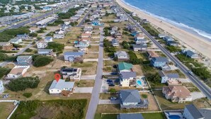 Vista aérea de una zona residencial costera con casas, carreteras y una playa.