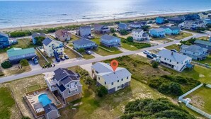 Vista aérea de una zona residencial costera con casas, piscina y una playa al fondo.