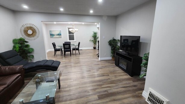 Una sala de estar moderna con una mesa de centro de vidrio, un sofá de cuero y un televisor de pantalla plana.