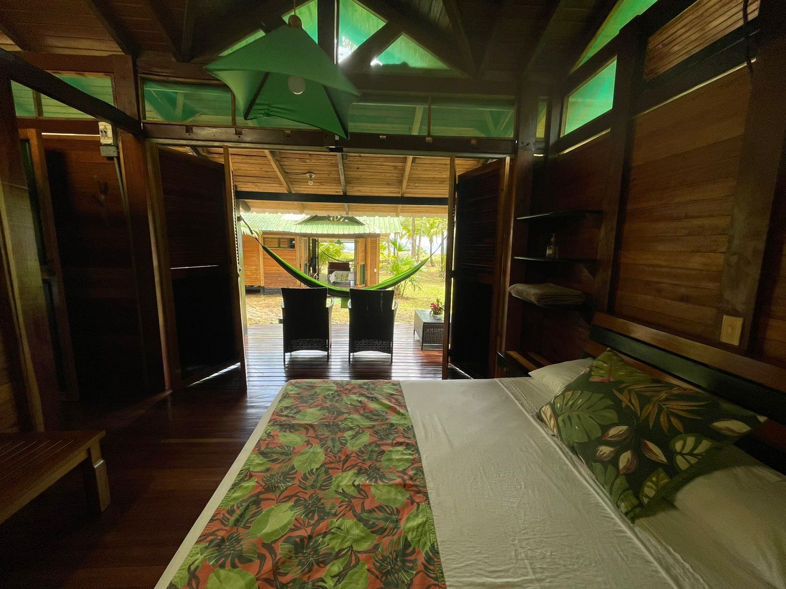 A room with a bed, a hammock, and a view of the outdoors.