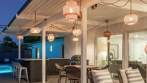 Une terrasse extérieure avec un espace bar, des sièges et une piscine.