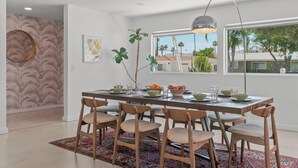 Un espace repas moderne avec une table en bois, dressée pour six personnes, et entourée de chaises assorties.