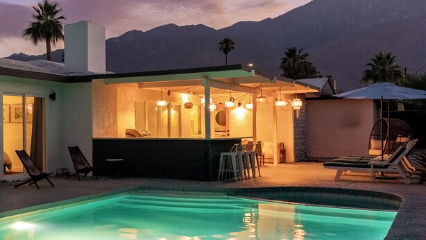 Une maison moderne dotée d’une piscine, d’un espace salon extérieur et offrant une vue sur les montagnes.