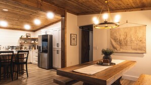 Una cocina moderna con piso de madera, una isla central y una lámpara colgante.
