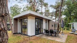 Una baita moderna e compatta con un patio attrezzato con tavolo e sedie.