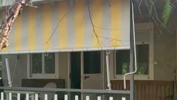 A building with a yellow and white striped awning, a white fence, and a door leading to a room. - Mobile home included in a complex of villas with swimming pool (Il Poggio)