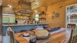 Un intérieur en bois comprenant une cuisine, un coin repas et une vue sur l’extérieur.