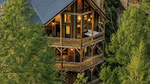 A multi-story wooden cabin with balconies, surrounded by dense foliage. - Birch Lodge by Avantstay Indoor Pool, Theater, Game Room & Stunning Views! (Gatlinburg)