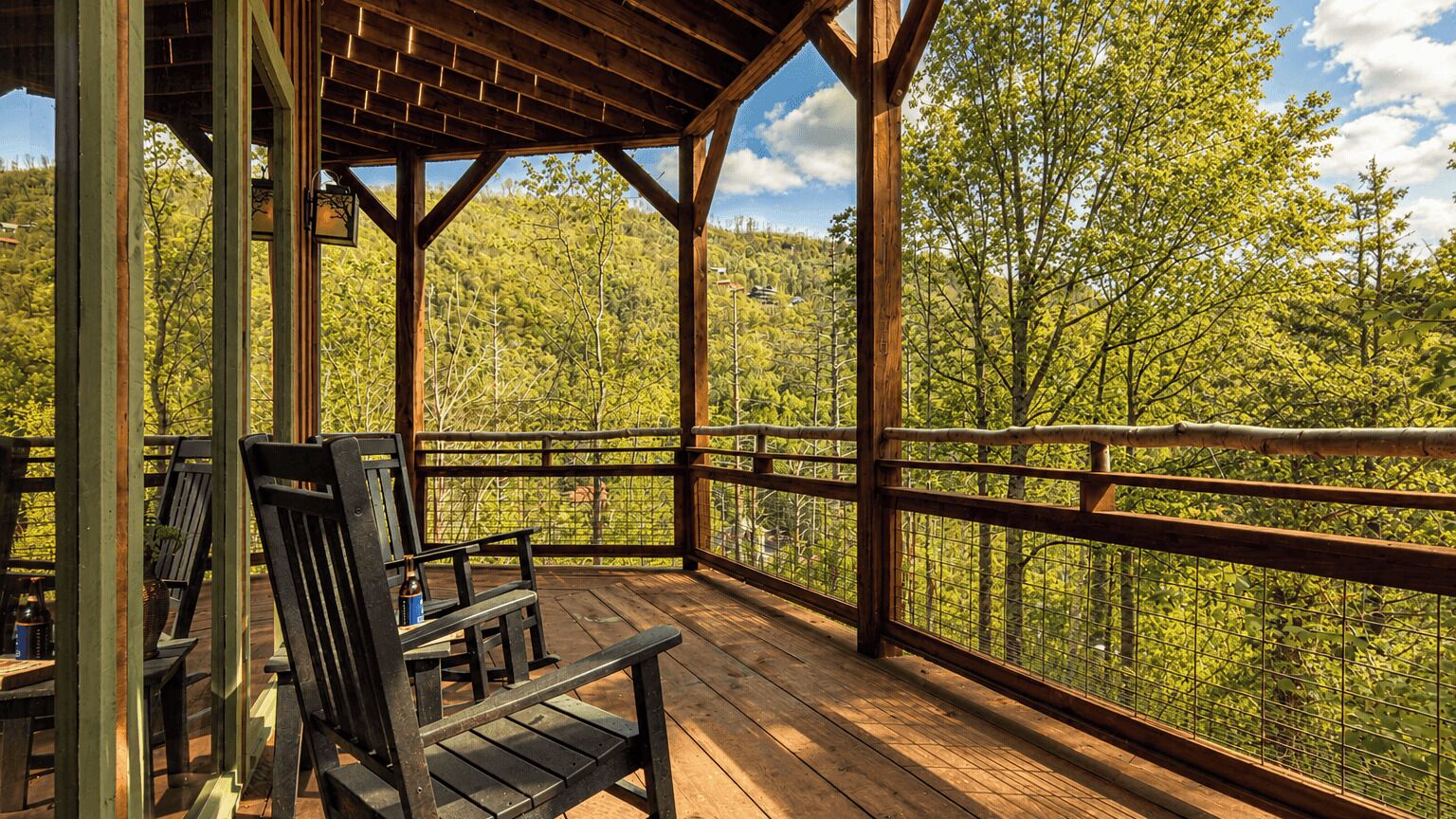 A wooden deck with benches and a view of a forested hillside.