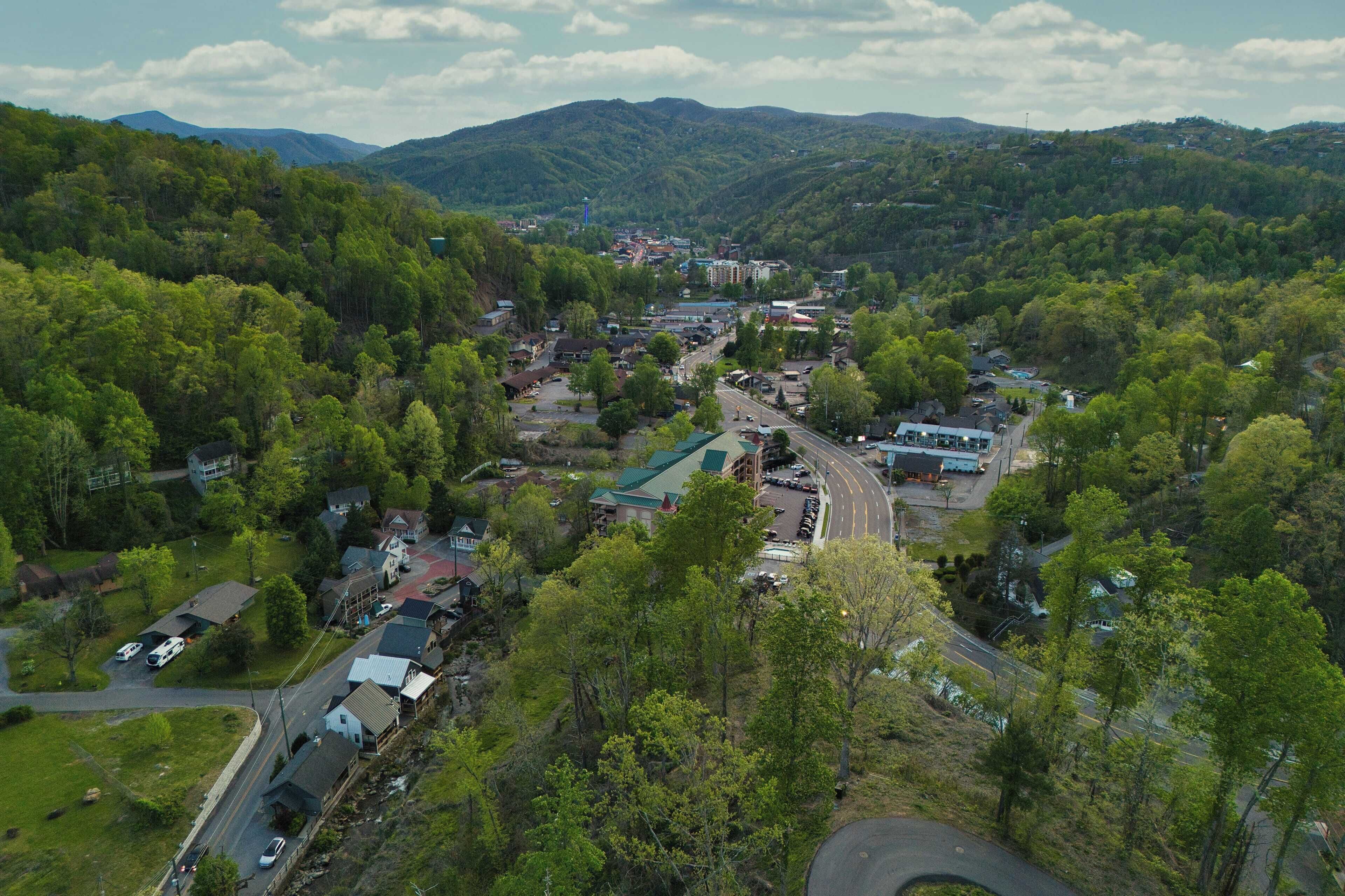 Un pueblo ubicado en un valle, con edificios residenciales y comerciales, rodeado de colinas verdes y exuberantes.