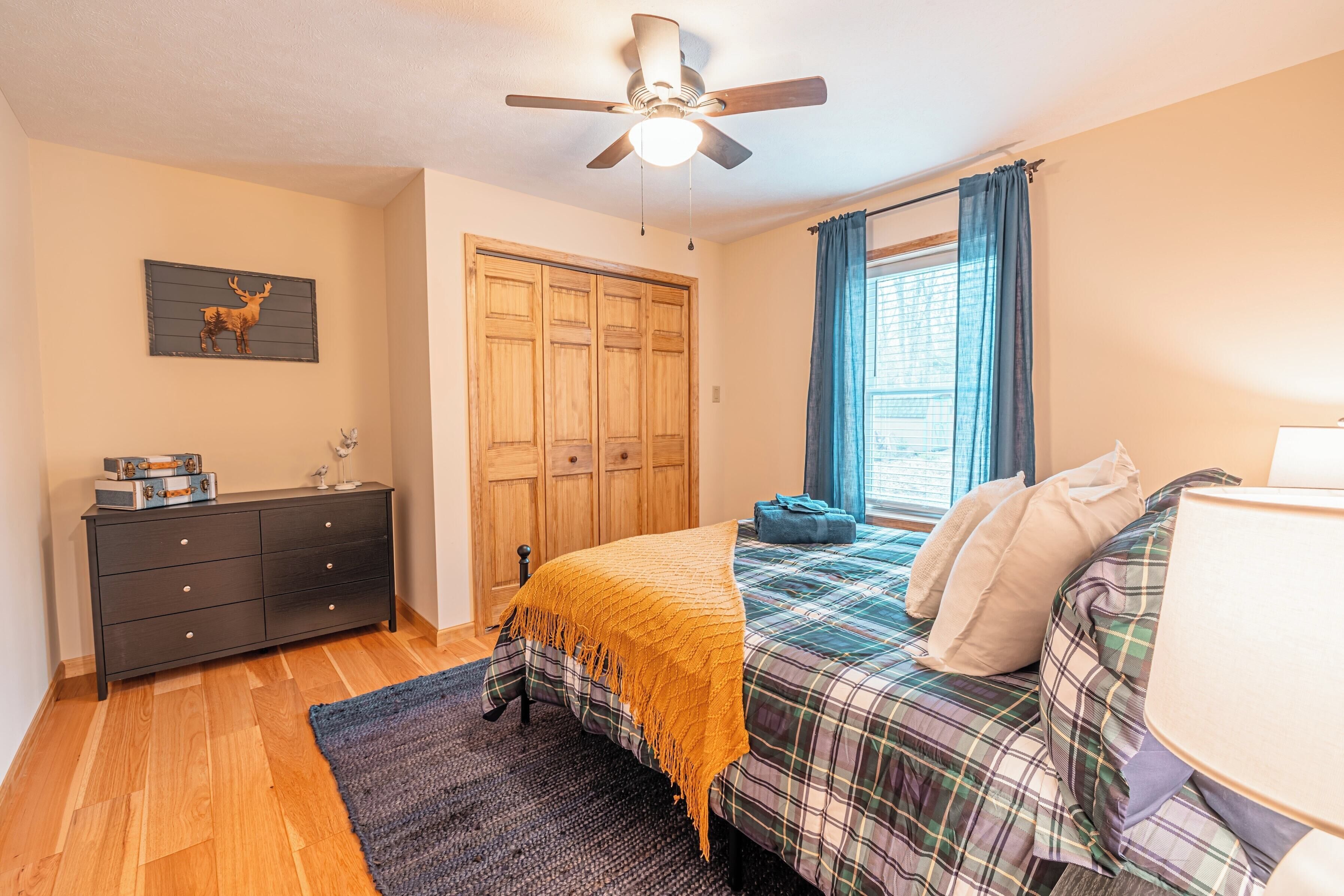 A bedroom with a bed, dresser, and a ceiling fan.