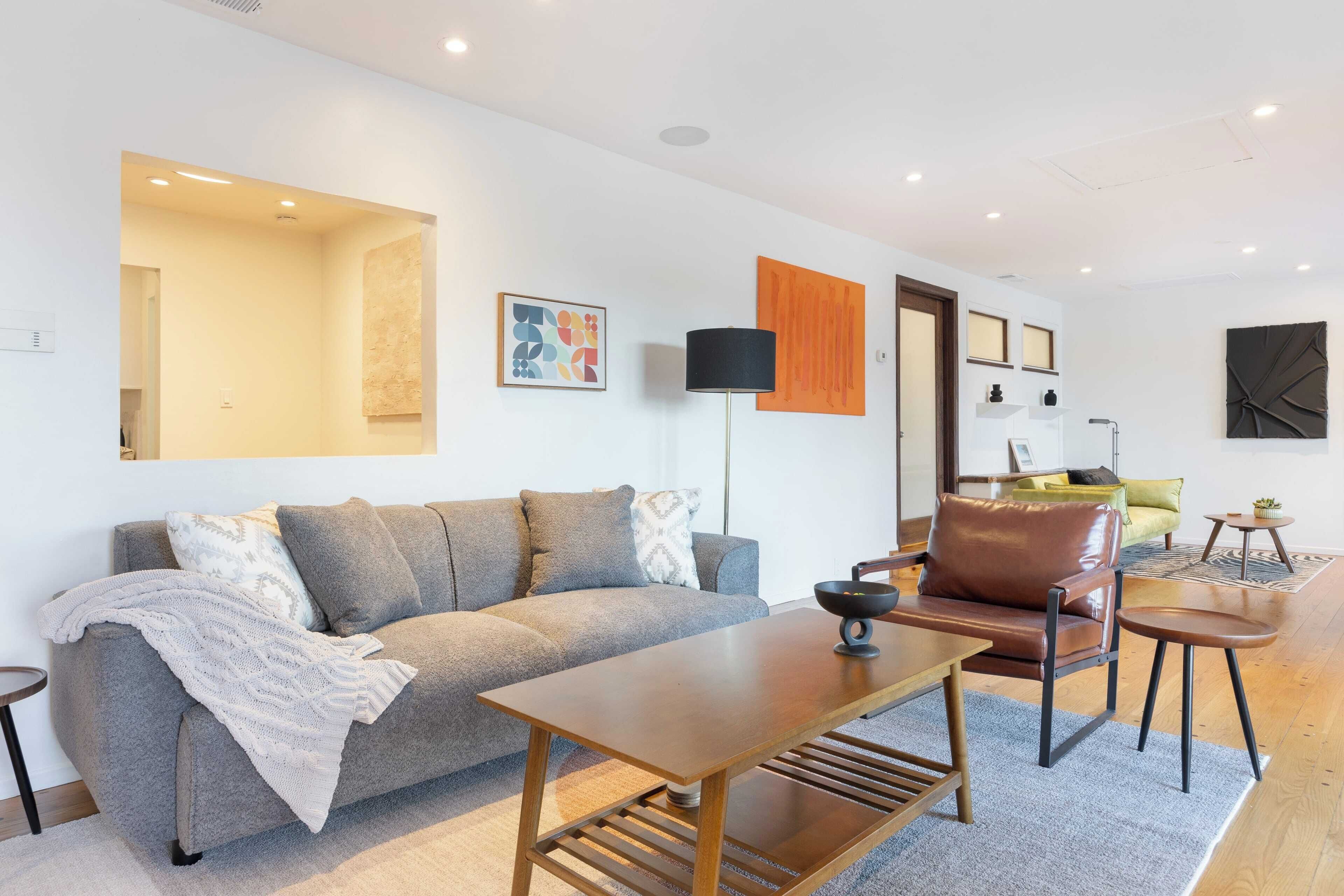 A modern living room with a grey sofa, a wooden coffee table, and a brown leather chair.