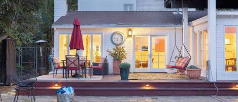 Una casa con un patio, mobiliario exterior, un reloj y una silla colgante.