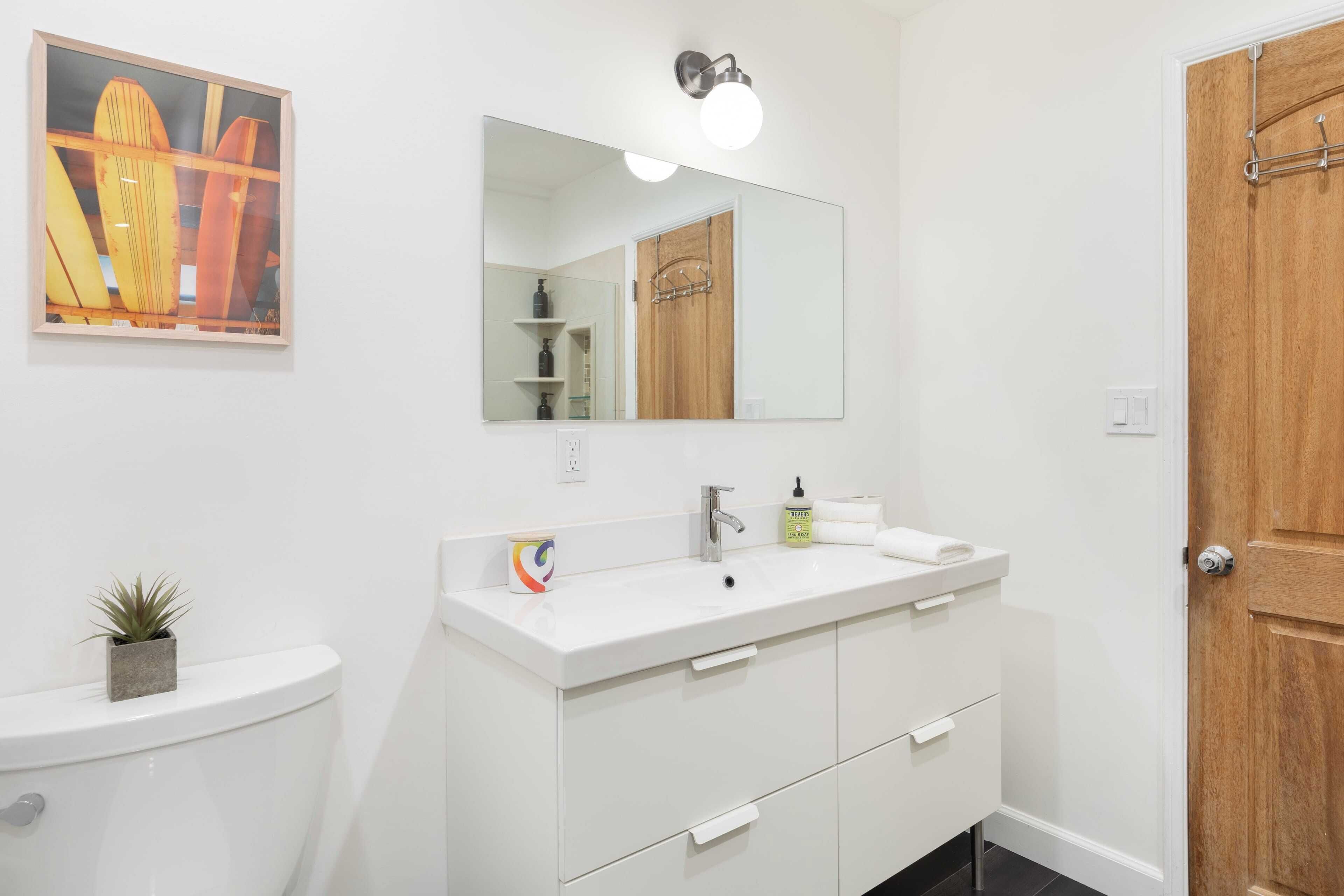 Une salle de bain avec un lavabo blanc, un miroir et une porte en bois.